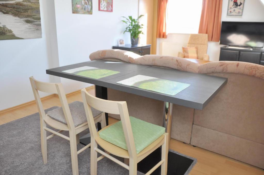einen Tisch und Stühle im Wohnzimmer mit Sofa in der Unterkunft Atelier Grünfink Ferienwohnung in Clausnitz