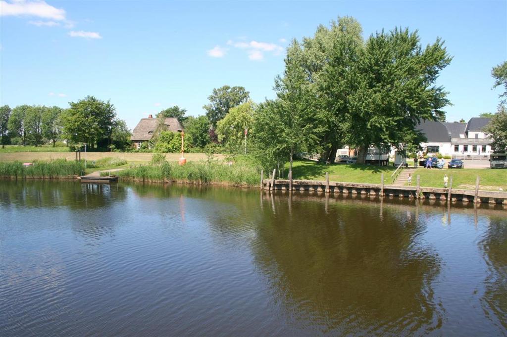 a river with a wooden dock in a park at Fährhaus Schwabstedt in Schwabstedt