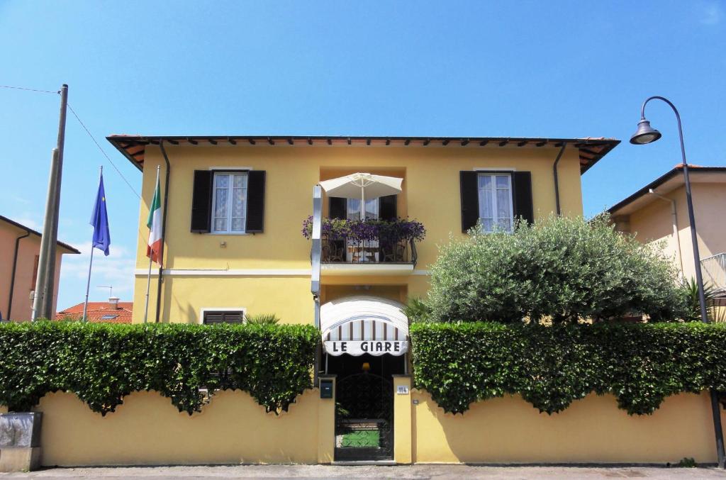 uma casa amarela com um portão branco e arbustos em Hotel Le Giare em Marina di Pietrasanta