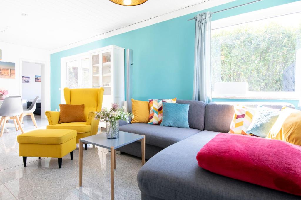 ein Wohnzimmer mit einem grauen Sofa und gelben Stühlen in der Unterkunft Kleine Strandpiraten in Grömitz