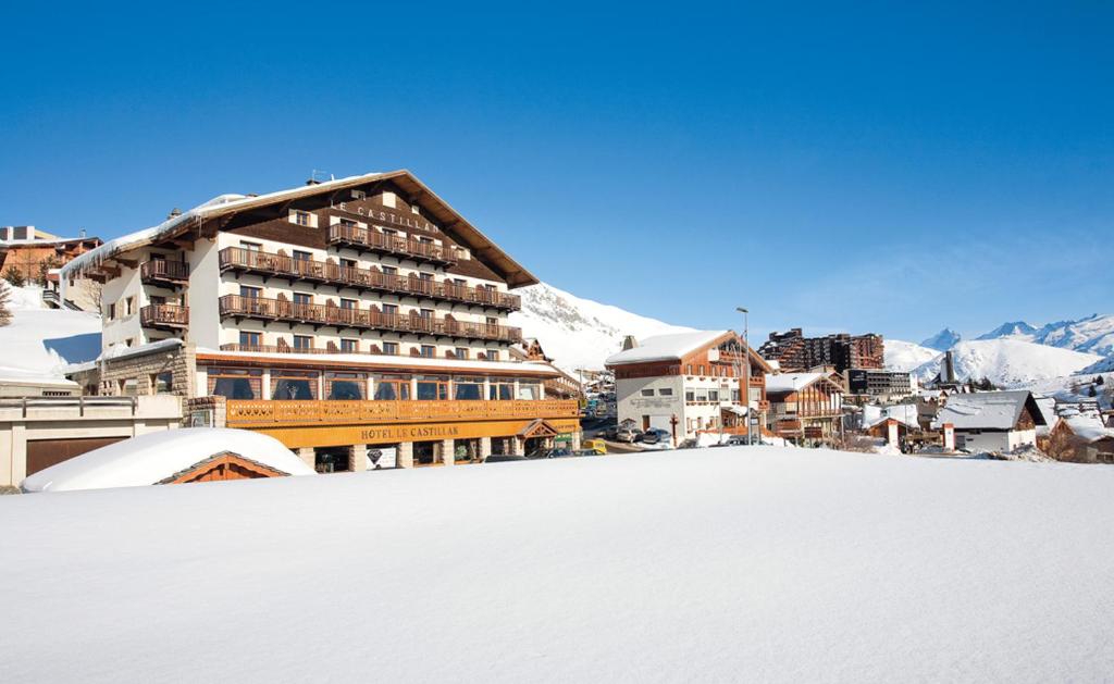 un gran edificio en la nieve junto a una montaña en Le Castillan en L'Alpe-d'Huez