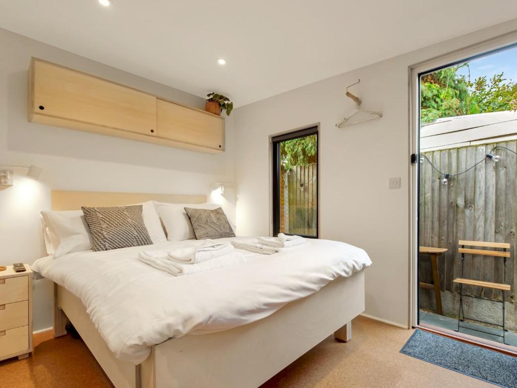 a bedroom with a large white bed and a window at Pass the Keys Whitstable Tiny house - a secret getaway! in Whitstable