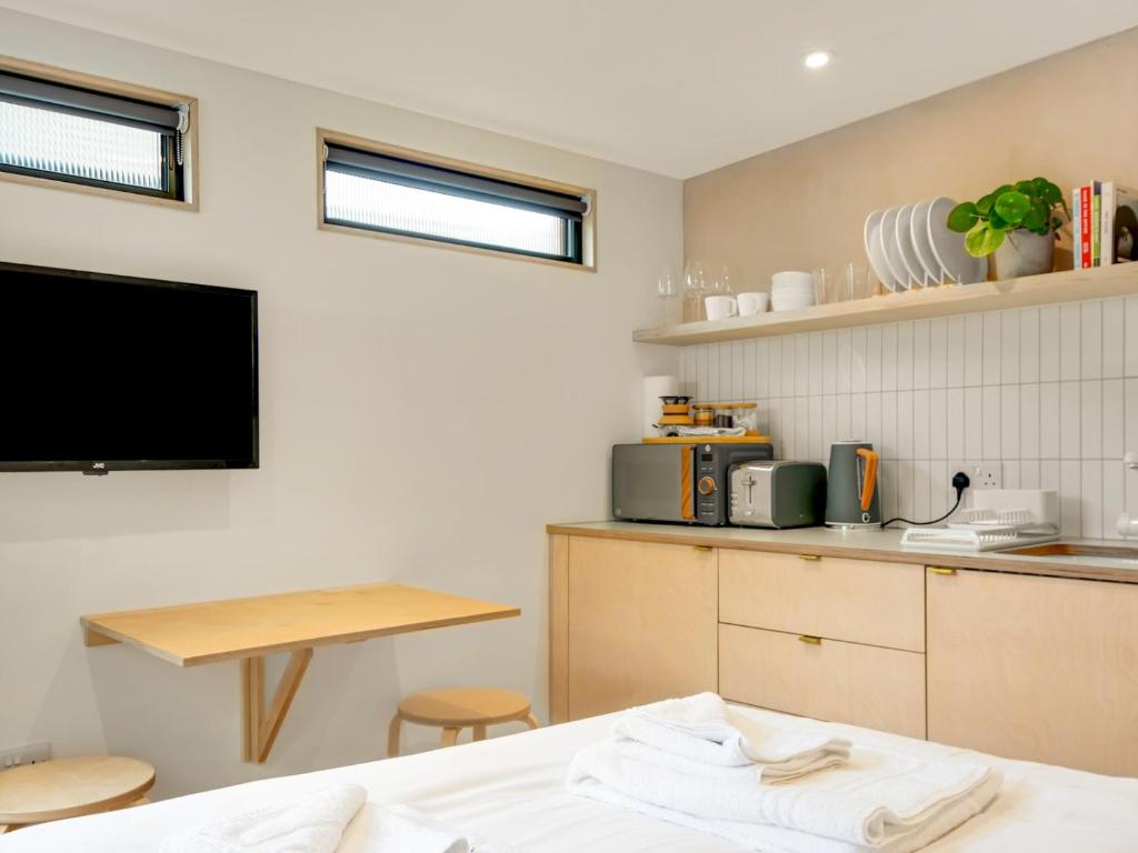 a kitchen with a bed and a table and a tv at Pass the Keys Whitstable Tiny house - a secret getaway! in Whitstable