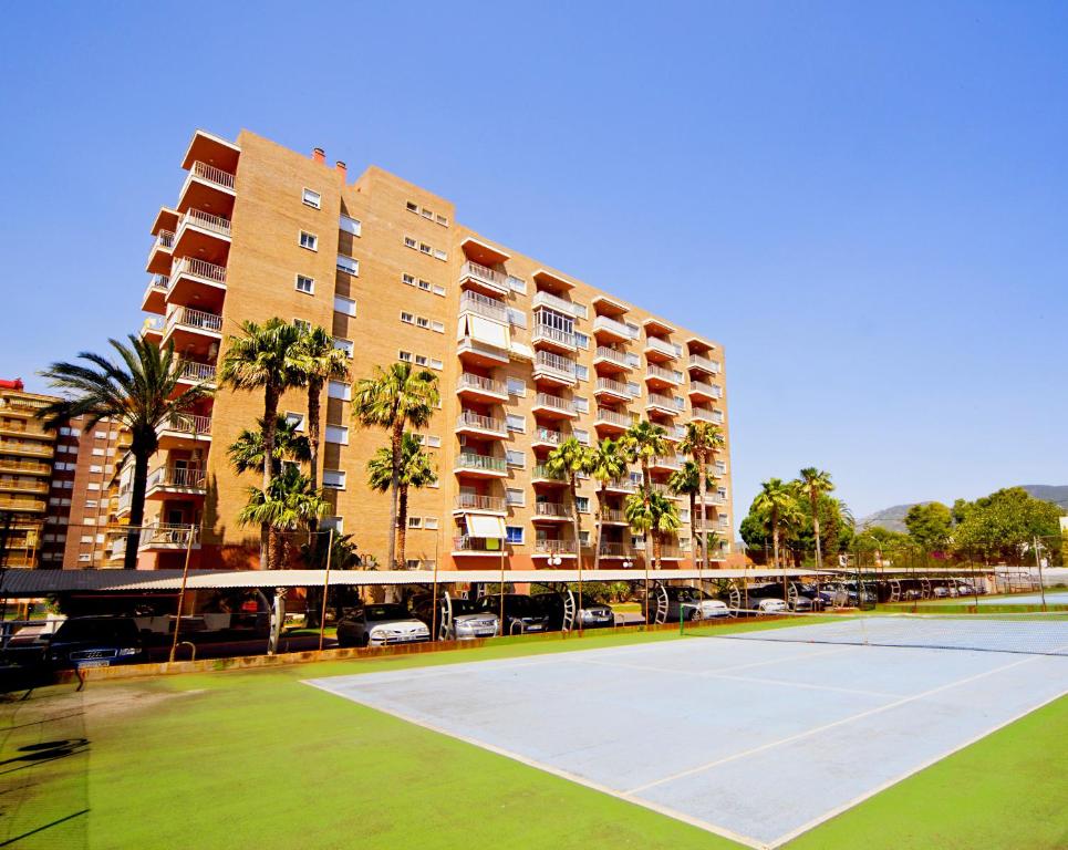 a tennis court in front of a large building at Bali Orangecosta in Benicàssim