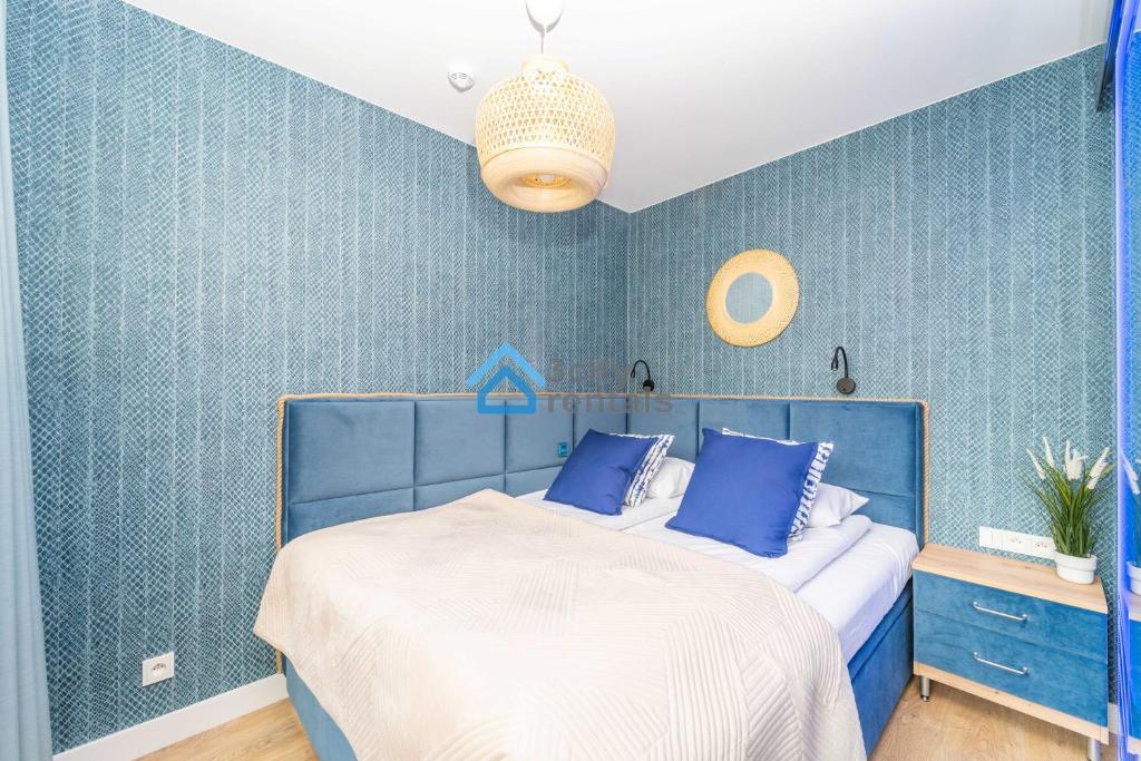 a blue bedroom with a bed and a blue wall at Navy Blue Superior Apartment in Gdynia