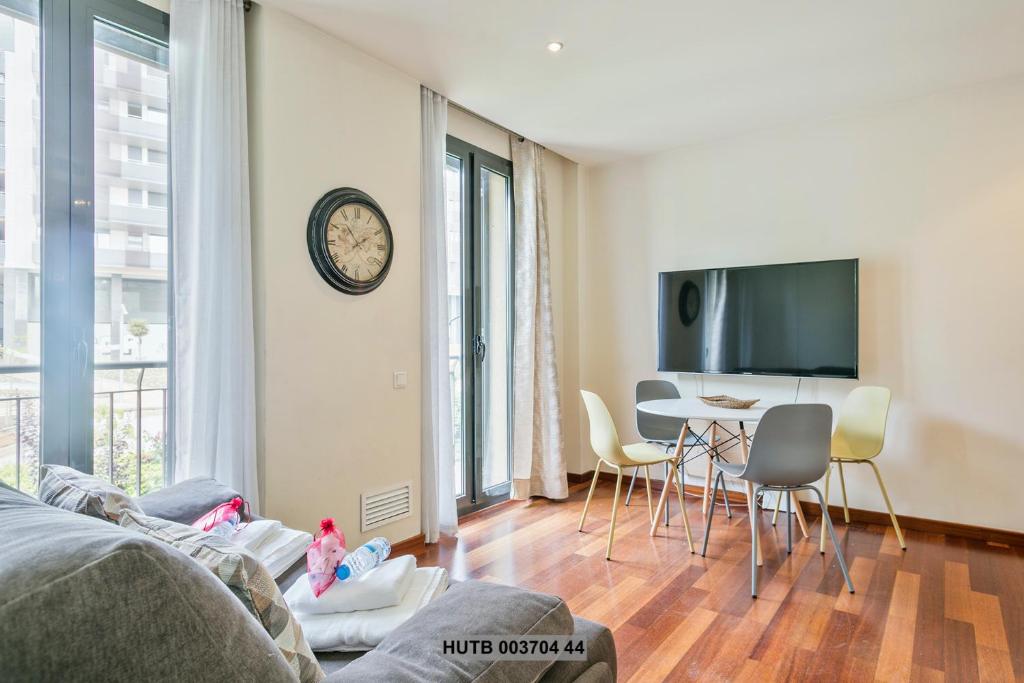 ein Wohnzimmer mit einem Tisch, Stühlen und einer Uhr in der Unterkunft Alcam Anglesola in Barcelona