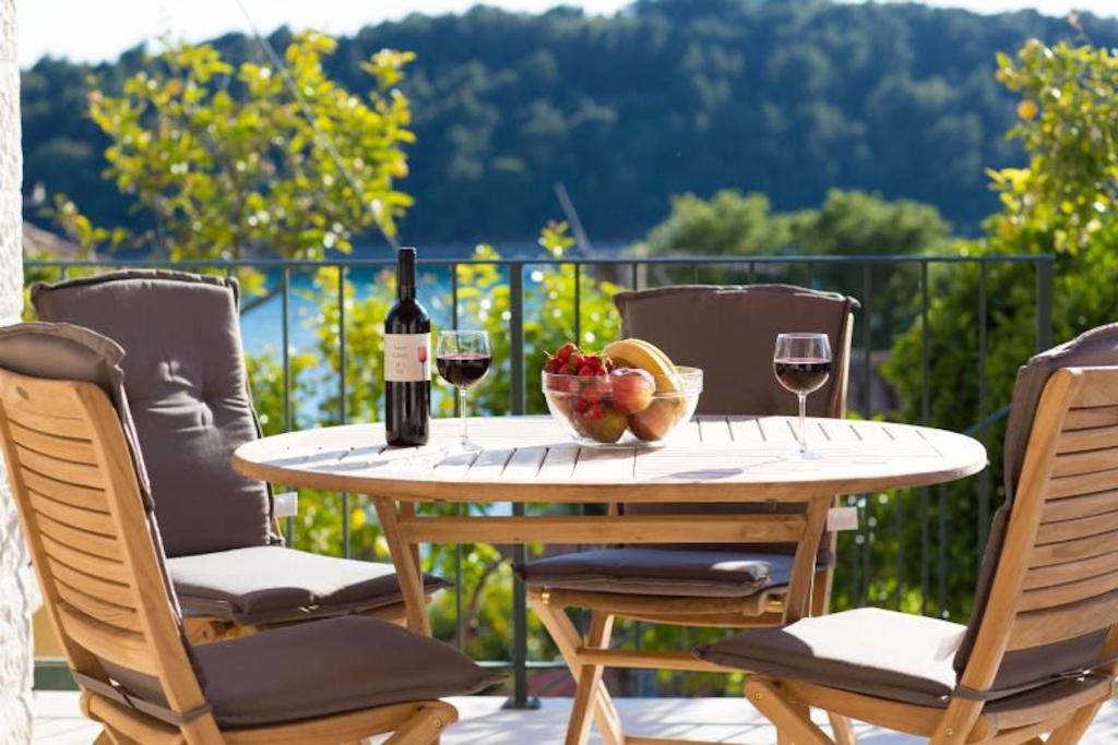 a table with a bowl of fruit and a bottle of wine at Sweet Old Stone House Cavtat in Cavtat