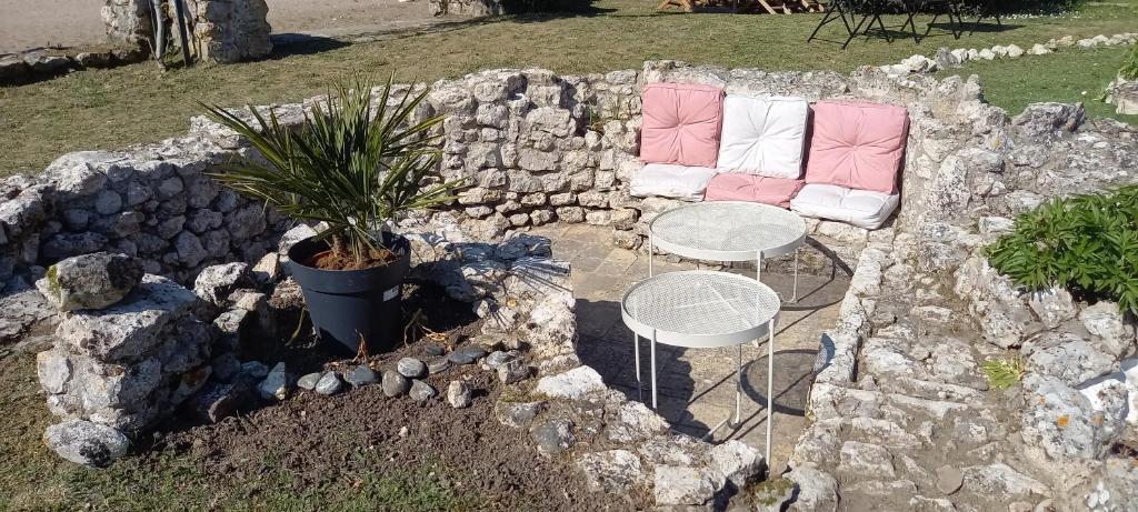 a stone wall with two chairs and a table and a plant at La Maison Josnes de Mady in Josnes