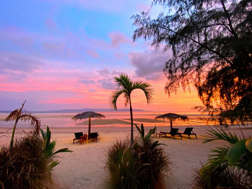 una spiaggia con sedie e ombrelloni al tramonto di SeaEsta Beach a Baan Tai