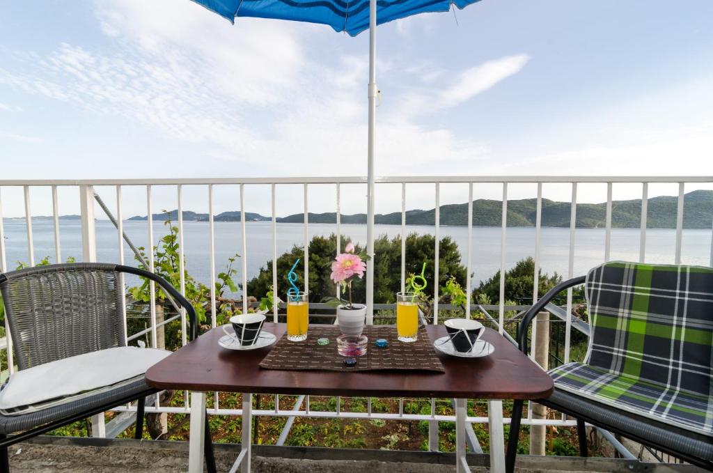 a table and chairs on a balcony with an umbrella at Apartment Giovani in Slano