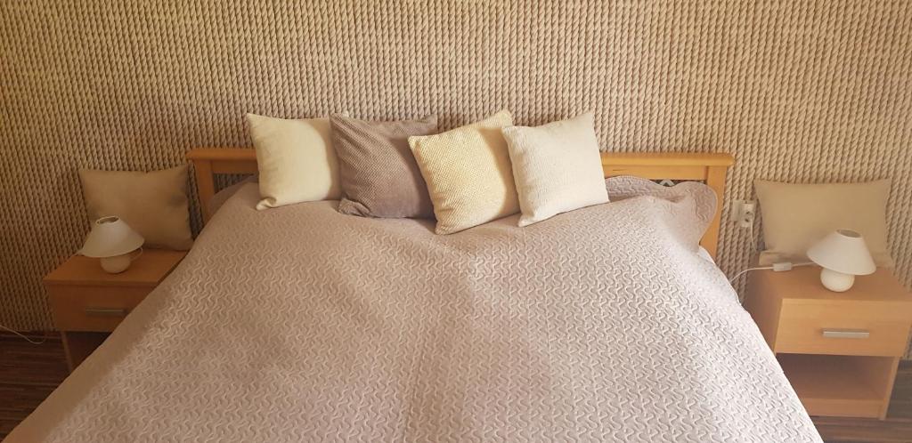 a bed with four pillows on it with two tables at Mimi Apartment in Nyíregyháza