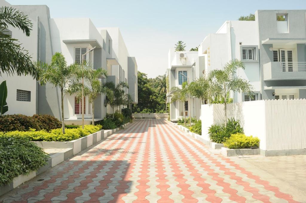 an empty street with white houses and trees at Leisure Stays - Premium Suites in Chennai