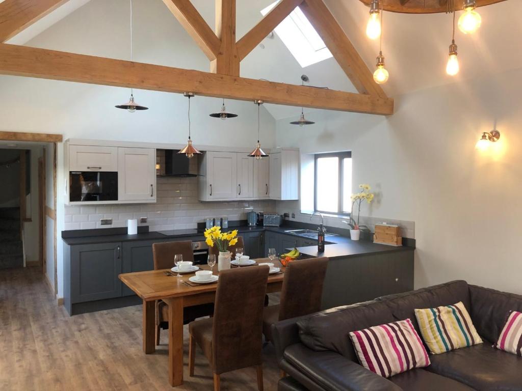 een keuken en een woonkamer met een tafel en een bank bij Newly Converted Luxury Barn With Private Hot Tub in Bodfari