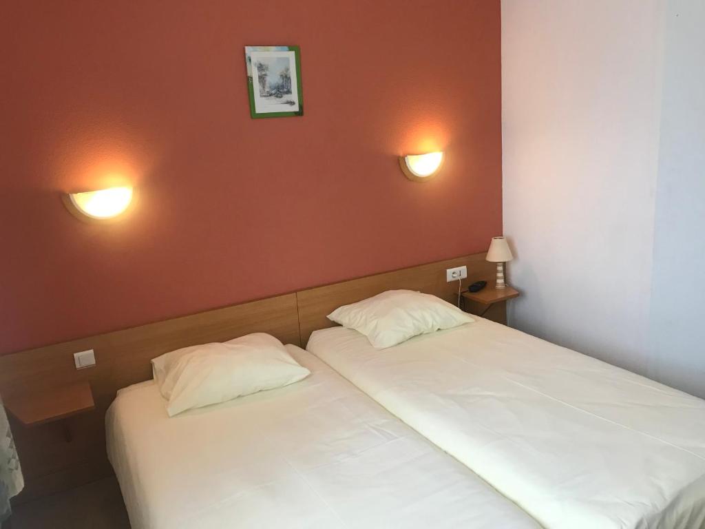 dos camas sentadas una al lado de la otra en una habitación en Hôtel Saint Augustin, en Mittelbronn