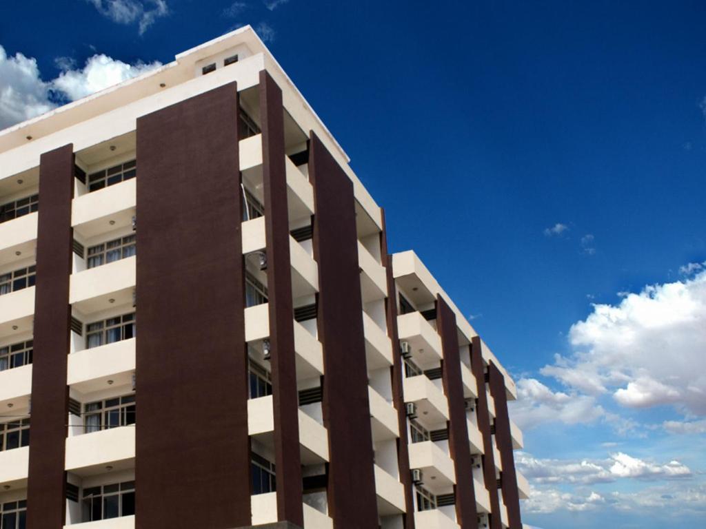 a tall white building with a blue sky in the background at Hotel Embaixador in Cruzeiro