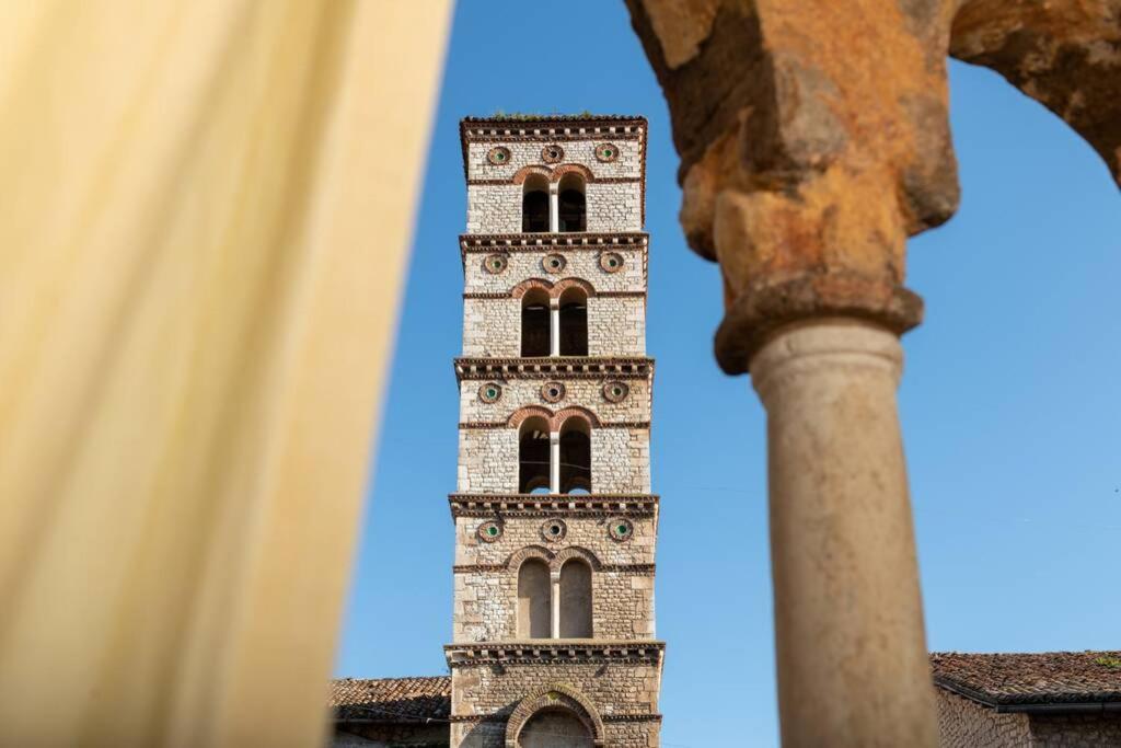 un edificio alto con una torre dell'orologio sullo sfondo di La Casa della bifora / The House of the mullion a Sermoneta