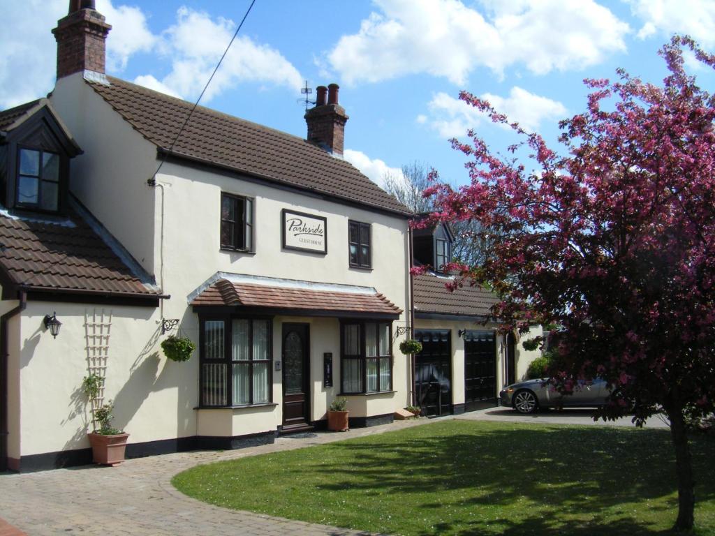 a white building with a flowering tree in front of it at Parkside Guest House in Pollington