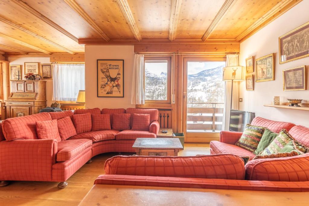 uma sala de estar com sofás vermelhos e uma grande janela em Casa Pecol em Cortina dʼAmpezzo