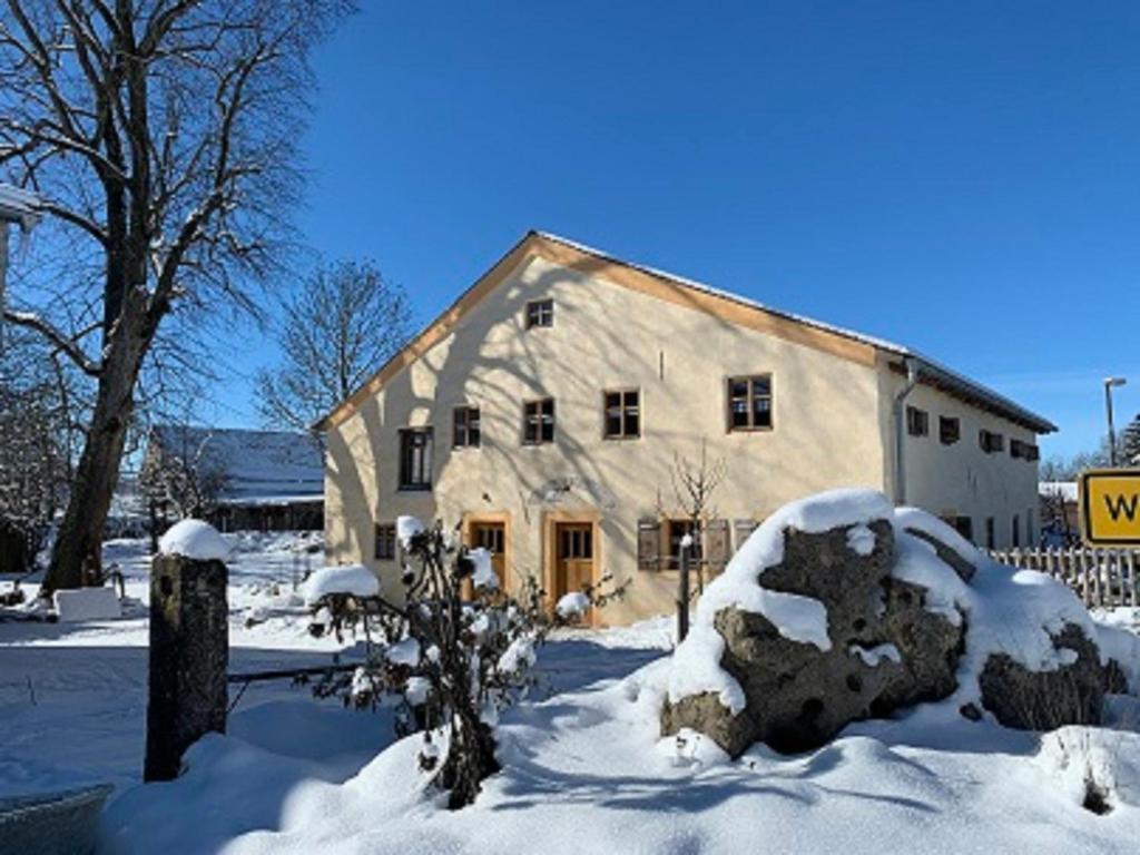a large stone building with snow on the ground at Ferienhaus Villa Kunnibunt in Burgsalach