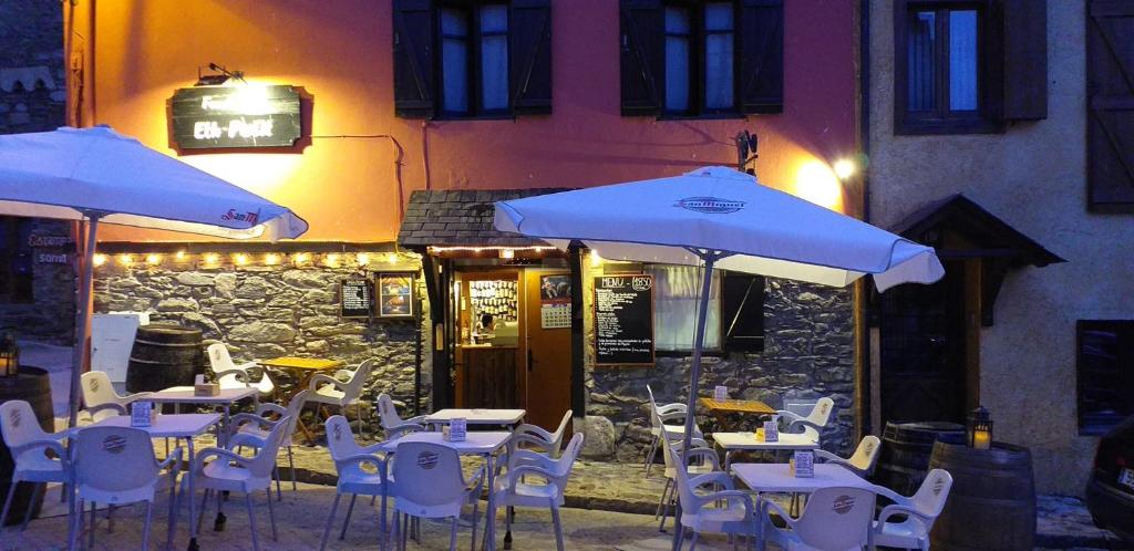 a group of tables and chairs with umbrellas outside a restaurant at Fonda Eth Petit - Sólo adultos,niños a partir de 12 años in Escuñau