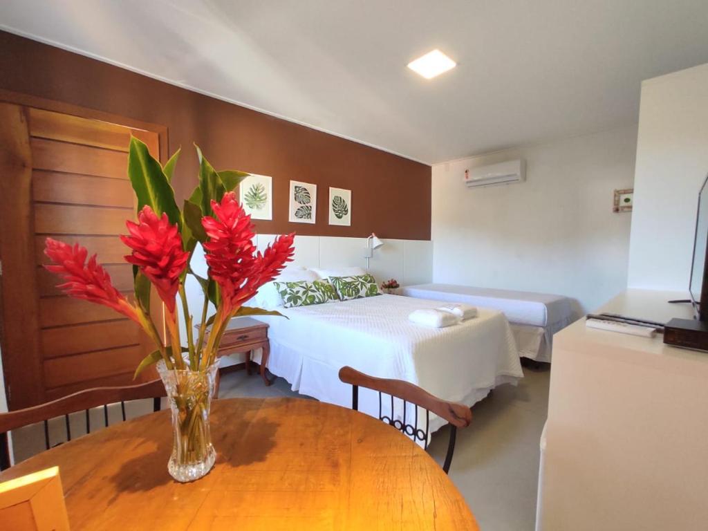 Habitación con cama y mesa con flores rojas en Terrazzo Suites, en Capitólio
