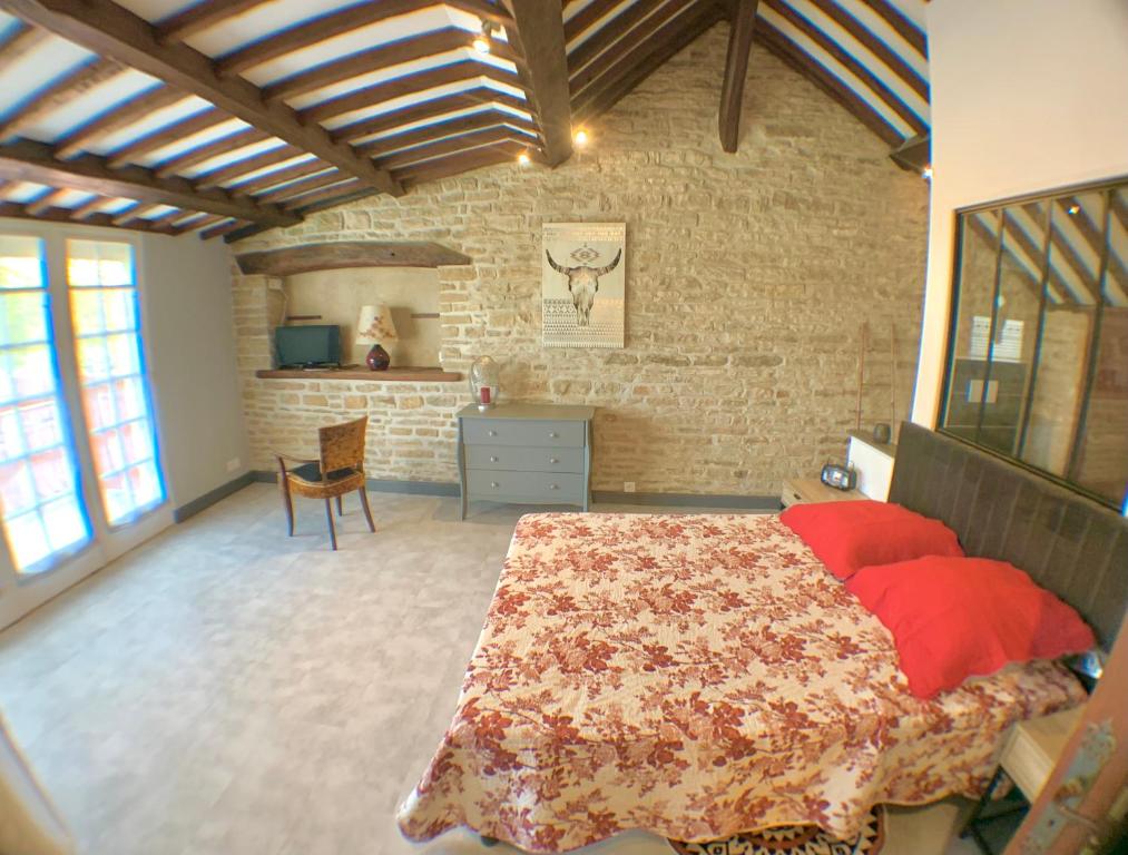 1 dormitorio con cama y pared de ladrillo en Le Clos Saint Gilles, T5, village viticole, en Ladoix Serrigny