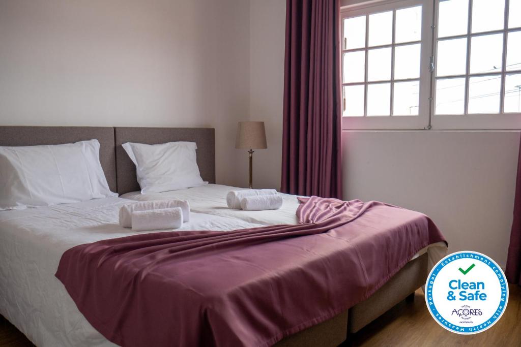 a bedroom with a large bed with a purple blanket at Casa da Relva in Ponta Delgada