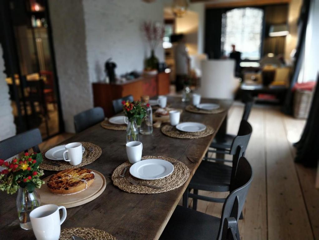 una larga mesa de madera con platos de comida. en La Gotale - Maison d' Amis, en Manhay