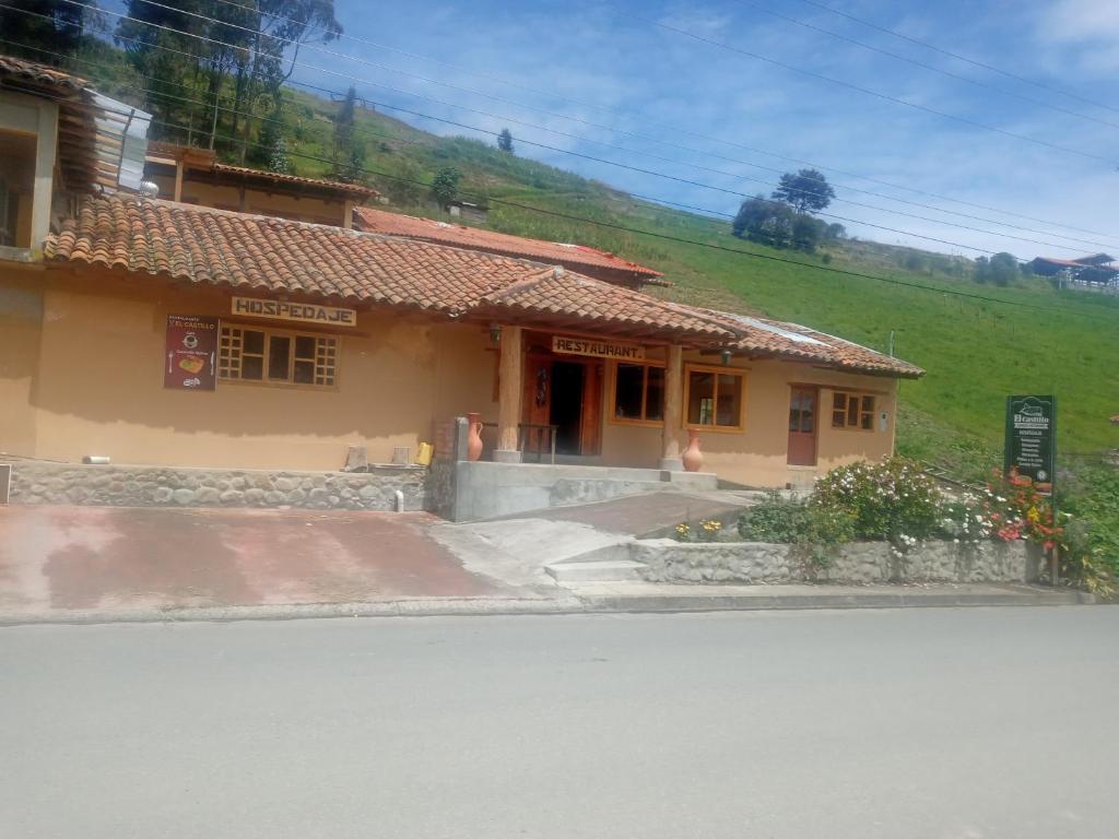a building on a hill next to a street at Hostal el castillo ingapirca in Ingapirca