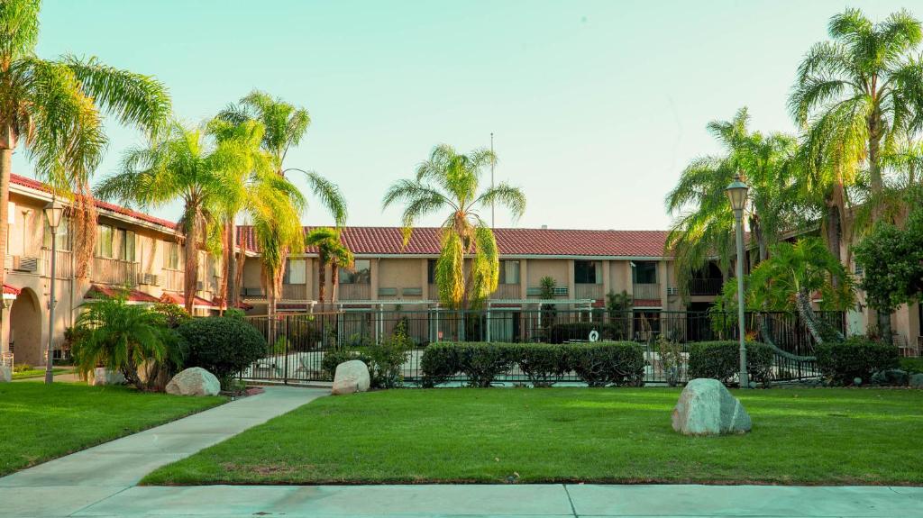 a building with palm trees and a yard with a park at Studio 6 Anaheim Hills CA in Anaheim