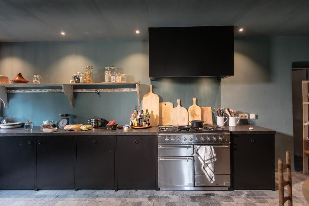 a kitchen with black cabinets and a stove at La Gotale - Maison d&#39; Amis in Manhay
