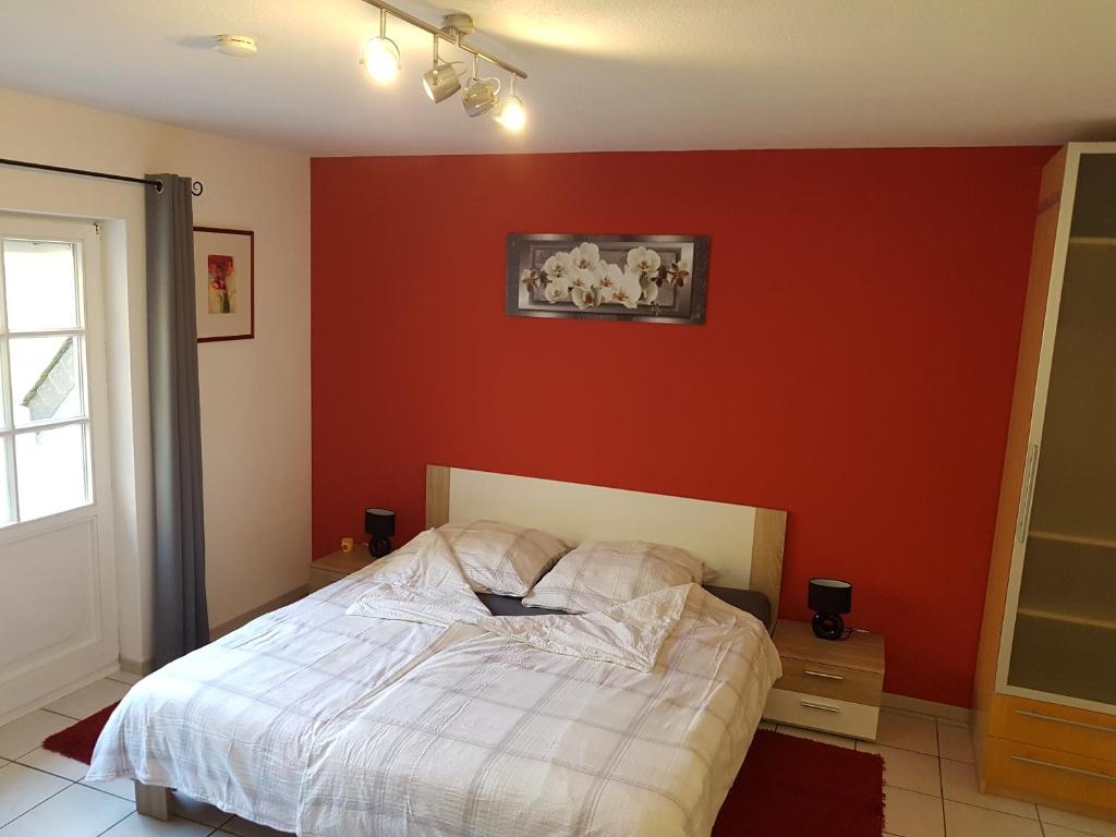 um quarto com uma cama e uma parede vermelha em Zimmerappartement "Rose" - Ferienwohnungen Wagner & Gaul em Falkenauel
