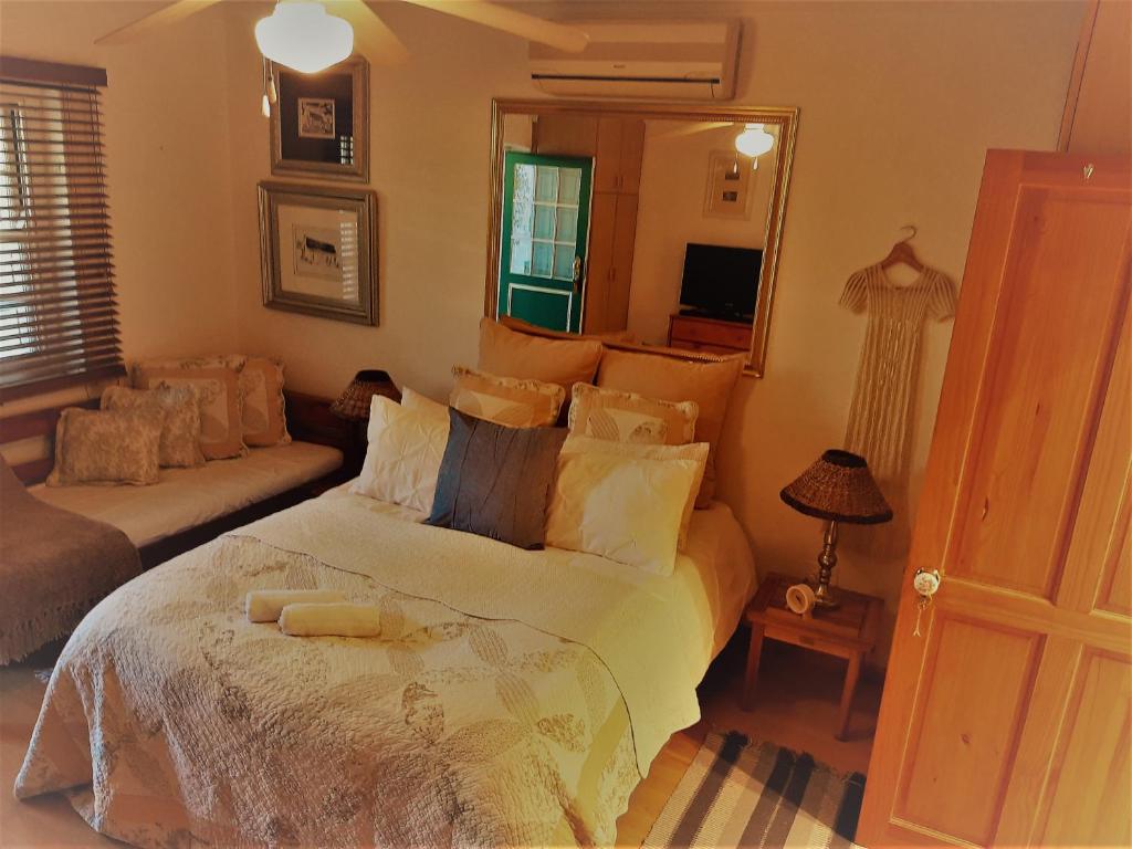 a bedroom with a bed and a couch and a mirror at Rosenhof Studio Five - When Privacy is Important in Clanwilliam