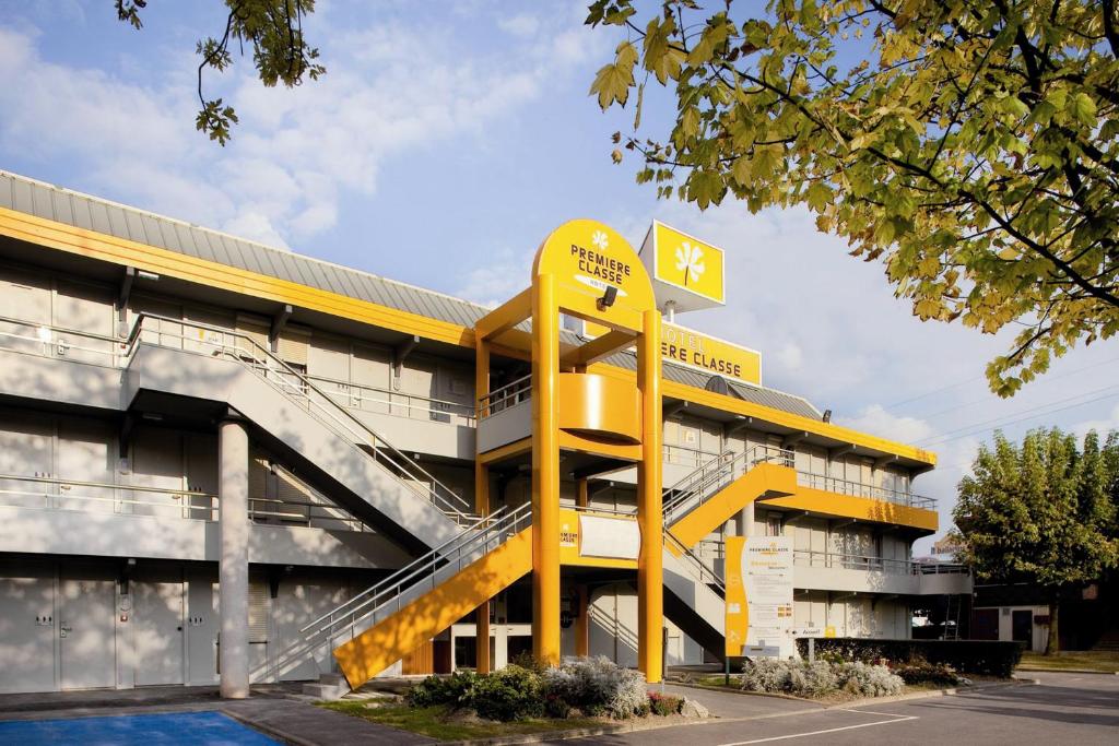 um edifício com um sinal amarelo em frente em Premiere Classe Lyon Est Aeroport Saint Exupery em Saint-Laurent-de-Mure