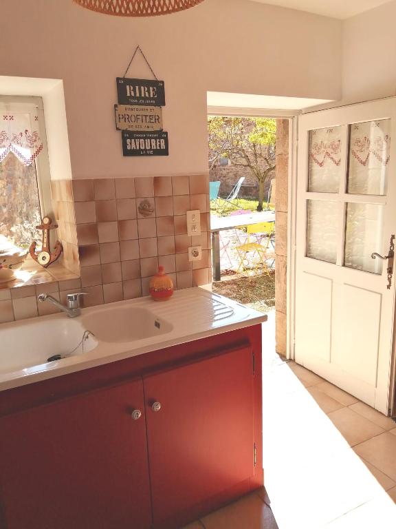 une cuisine avec un évier et une porte donnant sur une cour. dans l'établissement La Maison des Rosiers, à Manhac