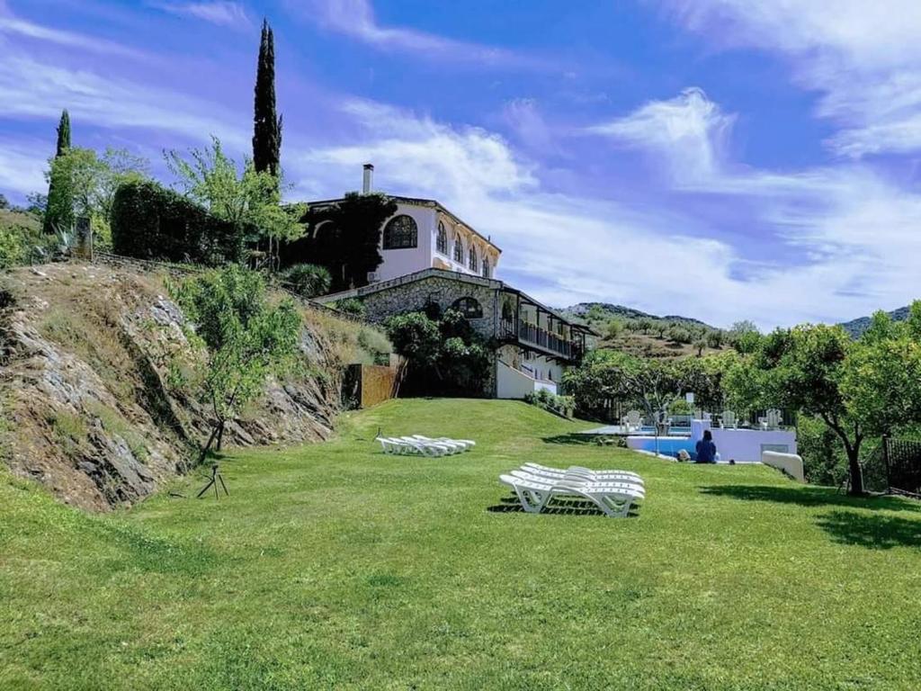 una casa en una colina con dos bancos en el césped en Posada Real Quinta de la Concepción en Hinojosa de Duero