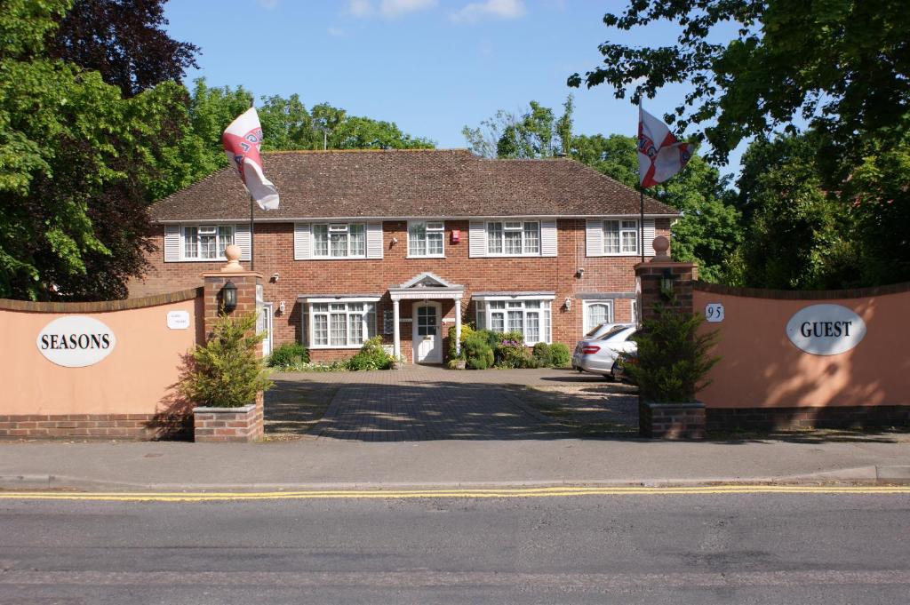 una casa de ladrillo rojo con dos banderas delante en All Seasons Gatwick Guest House & Parking en Horley