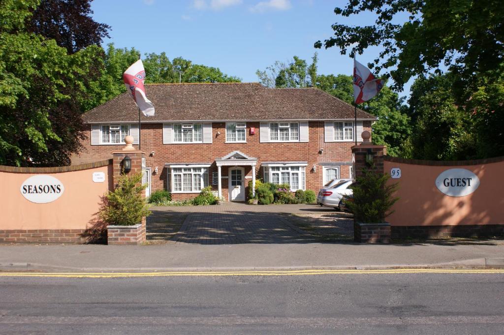 een rood bakstenen huis met twee vlaggen ervoor bij All Seasons Gatwick Guest House & Parking in Horley