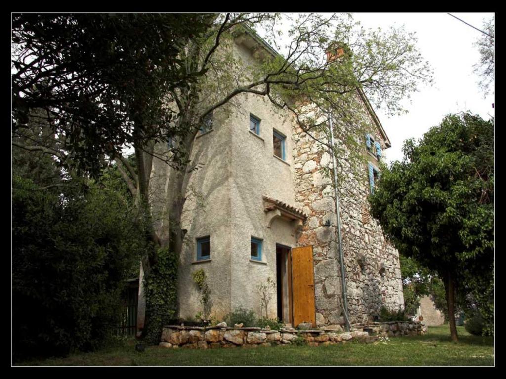 una antigua casa de piedra con una puerta de madera y árboles en Holiday Home Botanica, en Drenje