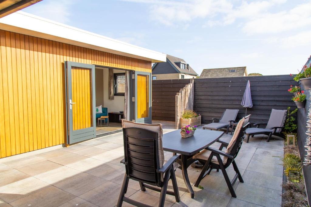 a patio with a table and chairs and a fence at Vrijstaande vakantiewoning Petite Renard in Zoutelande