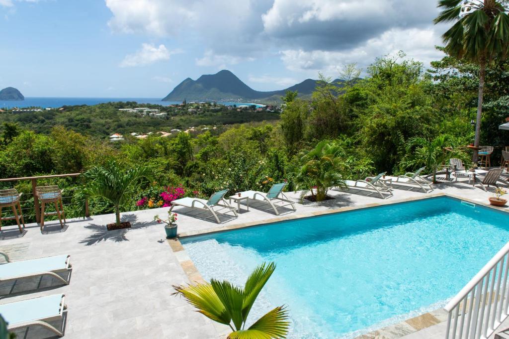 a pool with chairs and a view of the mountains at Kaz O'Rocher - Sea View Appartements in Le Diamant