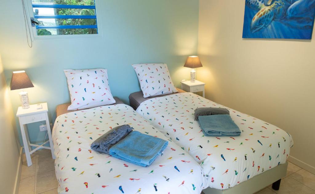 a bedroom with two twin beds in a room at Kaz O'Rocher - Sea View Appartements in Le Diamant