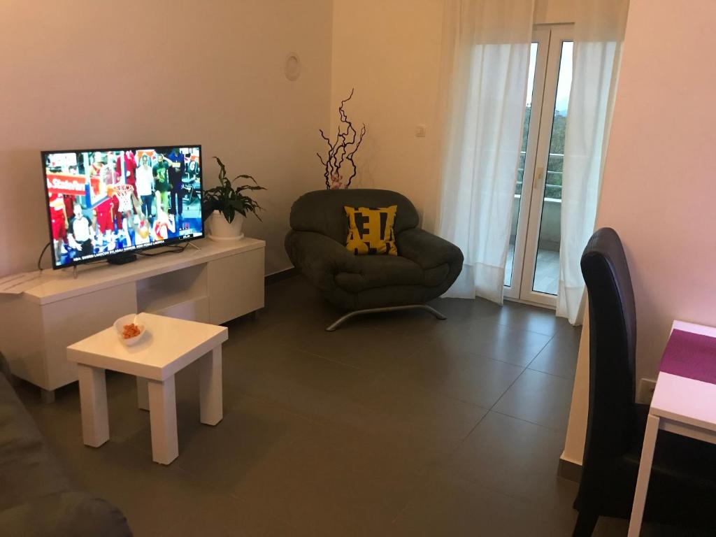 a living room with a chair and a flat screen tv at Apartment Doma in Međugorje