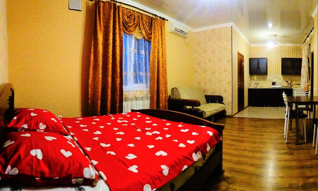a bedroom with a red blanket with white hearts on it at Stella Guest House in Anapa