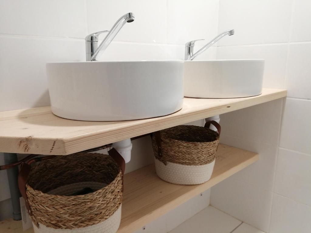 ein Badezimmer mit zwei Waschbecken und Körben auf einem Regal in der Unterkunft La Maison des Rosiers in Manhac
