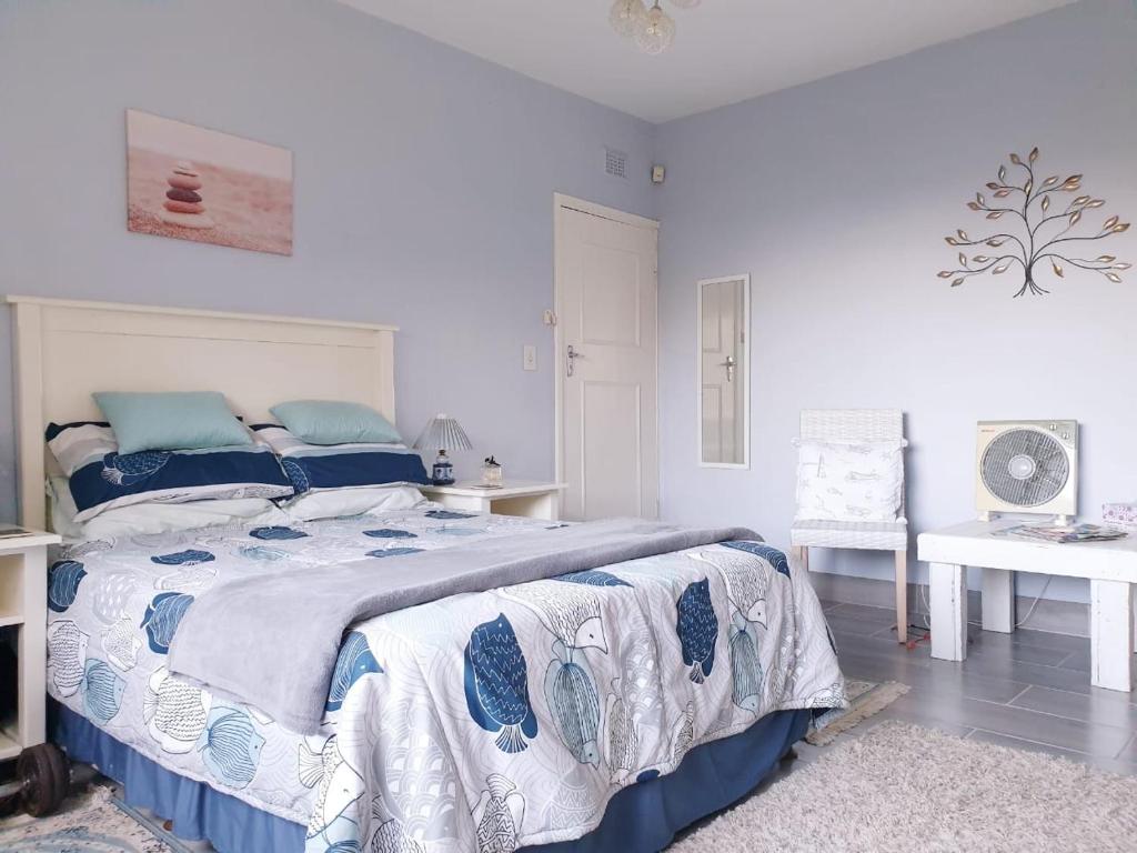 a bedroom with a bed with blue and white sheets at Whalehaven in Southbroom