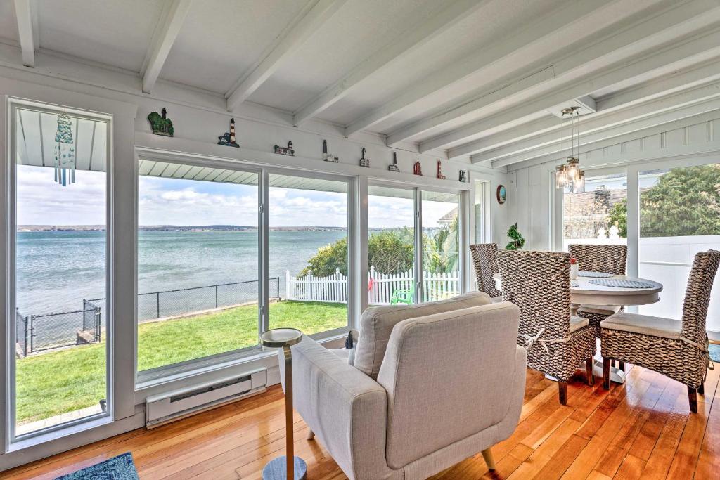 a living room with a table and chairs and windows at Waterfront Portsmouth Cottage 8 Mi From Newport! in Portsmouth