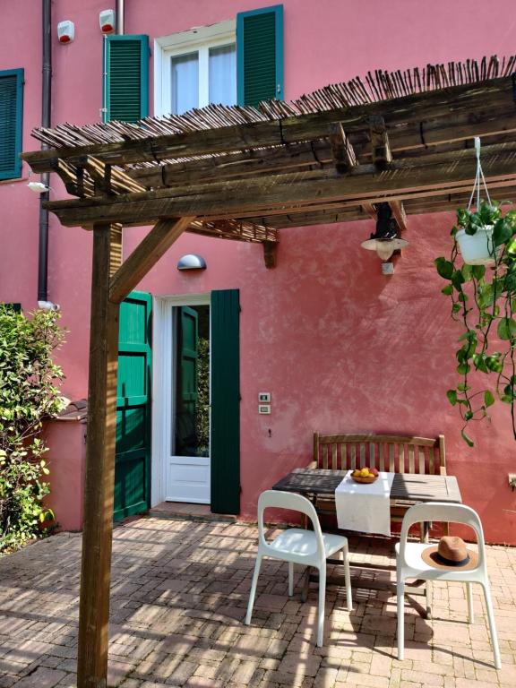 リパルベッラにあるAgriturismo Le Pellicceのピンクの家の前にテーブルと椅子付きのパティオ