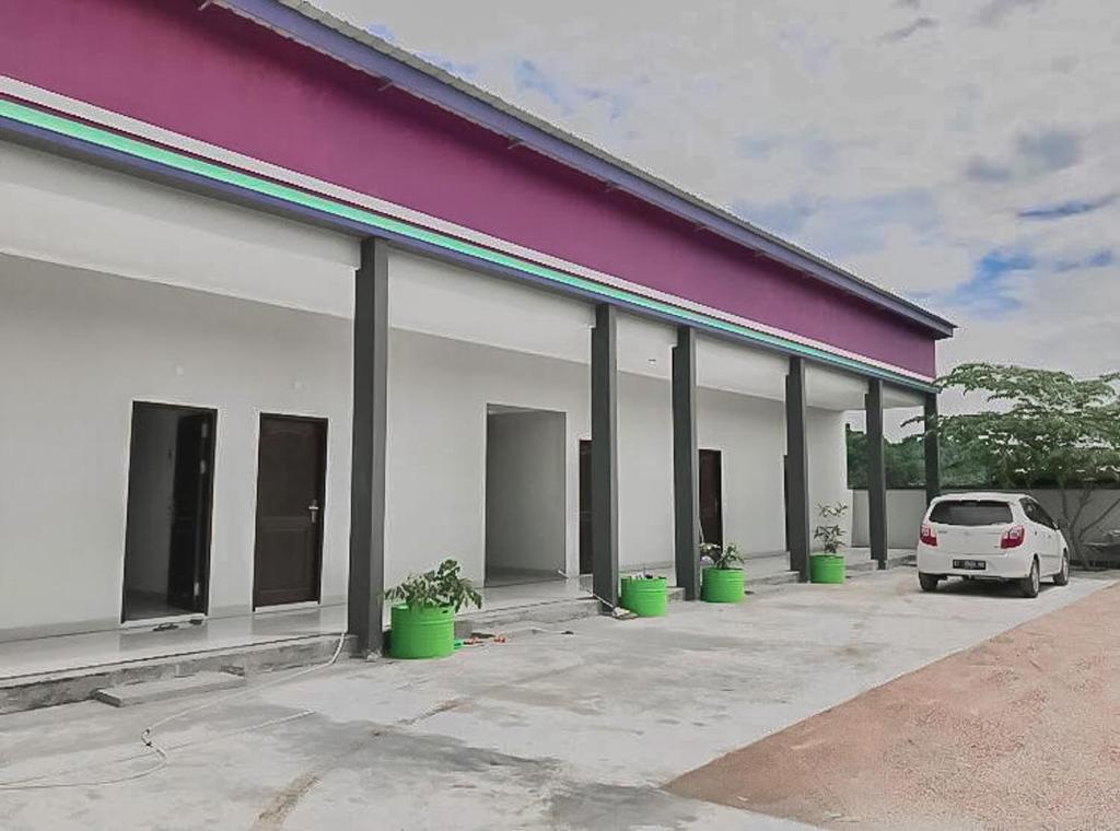 沙马林达Tiara Guest House Samarinda RedPartner的一辆白色汽车停在一栋建筑物前