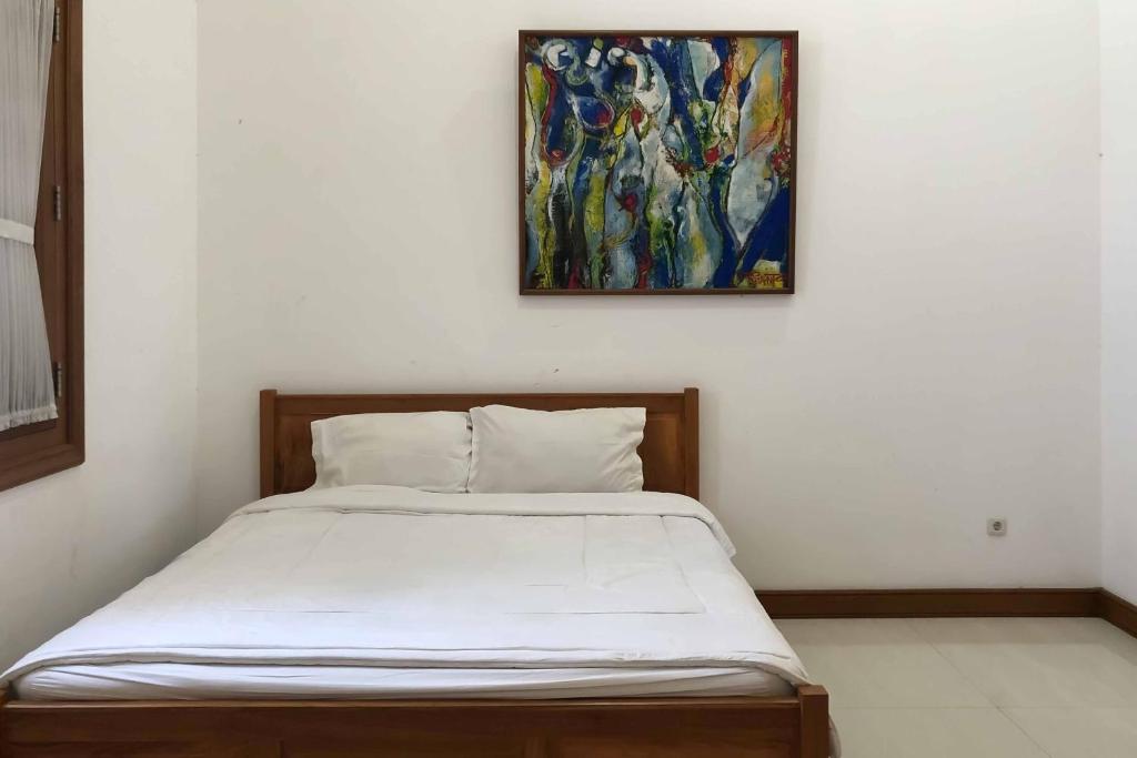 uma cama num quarto com uma pintura na parede em RedDoorz at Daffi Araya em Malang